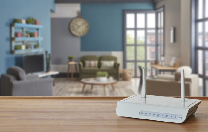Ein weißer WLAN Router steht auf einer Oberfläche in einer modern eingerichteten Wohnung.