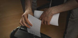 Ein Mann schreddert seine Unterlagen in einem Papierschredder.