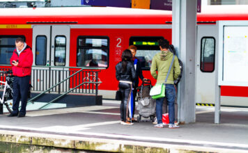 Fahrgäste am Bahngleis vor Zug der Deutschen Bahn.