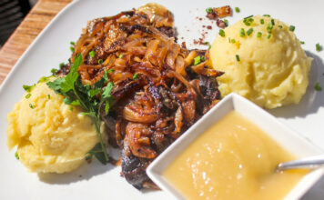 Nahaufnahme von klassichem Gericht: Sauerbraten mit Kartoffelpüree und Zwiebeln.