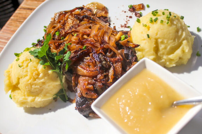Nahaufnahme von klassichem Gericht: Sauerbraten mit Kartoffelpüree und Zwiebeln.