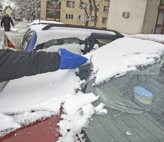 Ein Auto wird vom Schnee befreit.