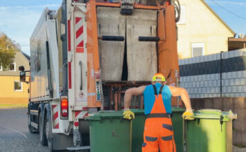 Müllarbeiter bringt Müllsäcke zum Müllwagen