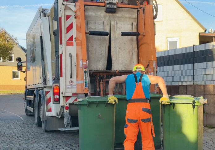 Müllarbeiter bringt Müllsäcke zum Müllwagen