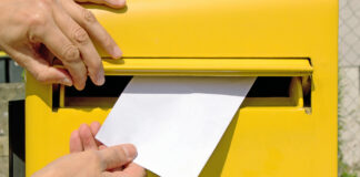 Ein Mann wirft einen Brief in einen öffentlichen Briefkasten