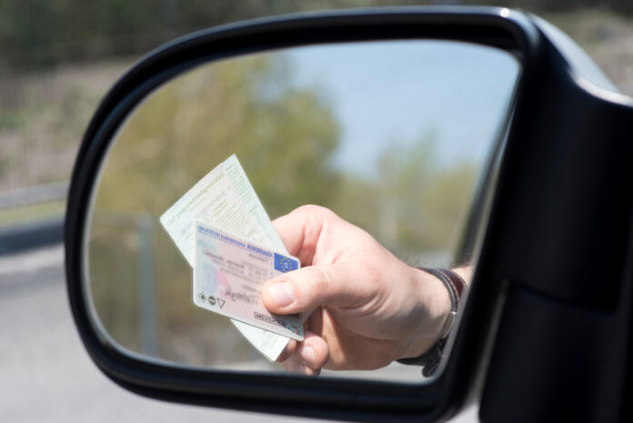 Ein Mann zeigt seinen Führerschein vor.
