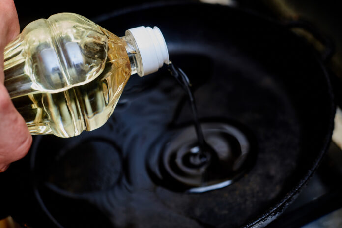 Öl aus Plastikflasche wird in eine Pfanne gegossen