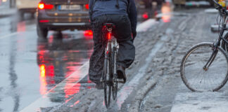 Fahrradfahren bei Wintereinbruch auf grauer Straße mit Schneematsch