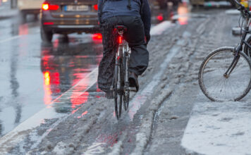 Fahrradfahren bei Wintereinbruch auf grauer Straße mit Schneematsch