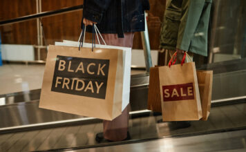 Zwei Personen halten Papiertüten mit Produkten vom Black Friday in der Hand