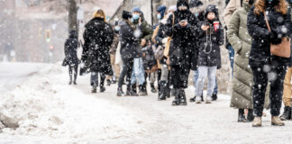 Viele Menschen stehen in einer Reihe im Winter bei Schnee in der Kälte an um etwas zu kaufen oder zu bekommen