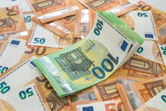 Viele Geldscheine liegen auf einem Haufen. Der Boden ist nicht zu sehen. Unten liegen viele orangefarbene 50-Euro-Scheine und oben sind einige grüne 100-Euro-Scheine gestapelt.