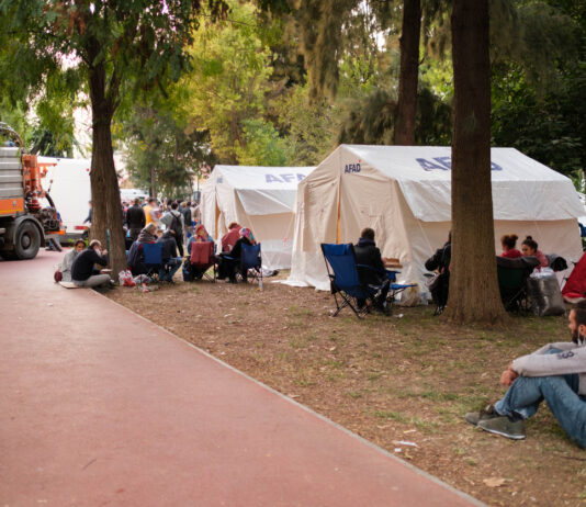Flüchtlinge sitzen am Rande einer Zeltstadt