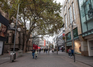 Viele Passanten bummeln durch eine Einkaufsstraße und shoppen in den verschiedenen Läden der Innenstadt