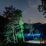 Ein Mann mit einer Kopflampe durchquert einen Wald mitten in der Nacht
