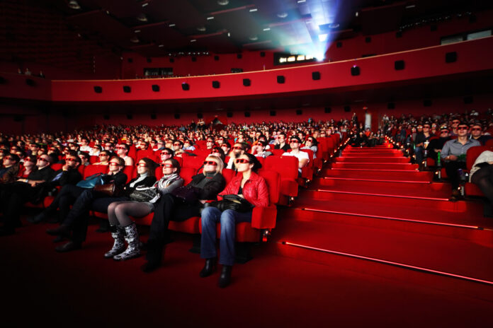 Mehrere Menschen sitzen in einem Kinosaal und schauen einen Film