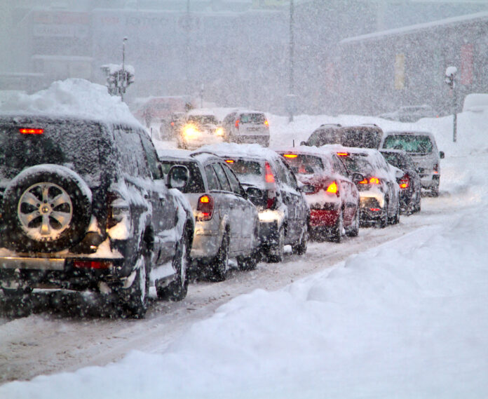 Viele Autos stehen im Stau auf einer zugeschneiten Straße. Eine Frostpeitsche trifft auf Deutschland.