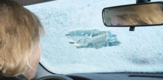 Eine Frau sitzt im Auto und die Scheibe ist gefroren.