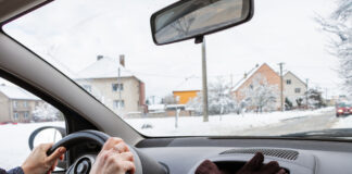 Eine Frau fährt im Winter Auto, die Handschuhe liegen in einem Fach im Amaturenbrett.