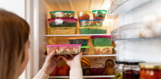 Eine Frau packt Lebensmittel in Tupperware in den Kühlschrank.