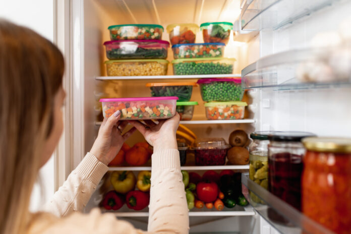 Eine Frau packt Lebensmittel in Tupperware in den Kühlschrank.