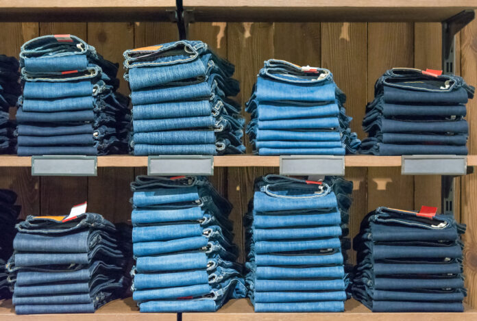Mehrere Jeans auf einem Regal in einem Jeans-Laden.