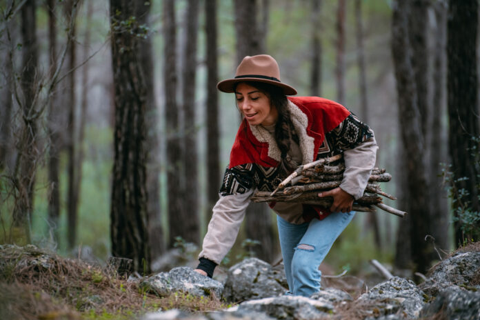 Junge Frau sammelt Holz im Wald.