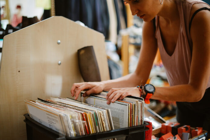 Eine Frau sieht sich in einer Kiste alte Schallplatten an.