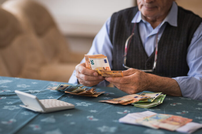 Ein Rentner sitzt an einem Tisch und zählt sein Geld.