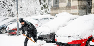 Ein junger Mann schippt Schnee nach Wetter-Wende.