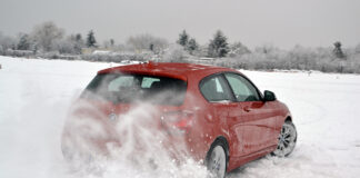 Ein Auto fährt durch eine Schnee-Landschaft im Winter.