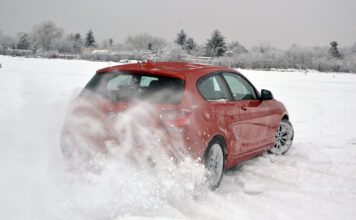 Ein Auto fährt durch eine Schnee-Landschaft im Winter.