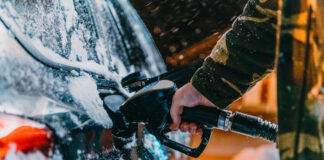 Ein Mann tankt im Winter an einer Tankstelle sein Auto.