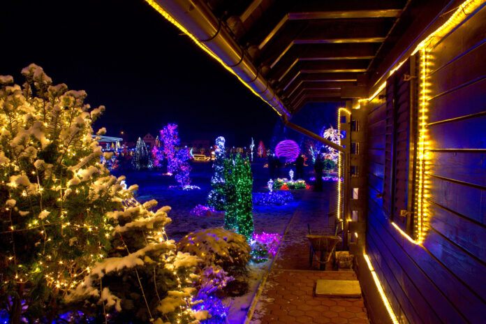 Die Sicht auf ein mit Weihnachtsdeko dekoriertes Haus und ein Garten voller Weihnachtslichter