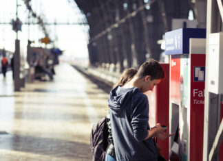 Eine Frau und ein junger Mann kaufen an einem Ticket-Automaten am Gleis an einem Deutschen Bahnhof ein Ticket für einen Regionalzug oder einen ICE.