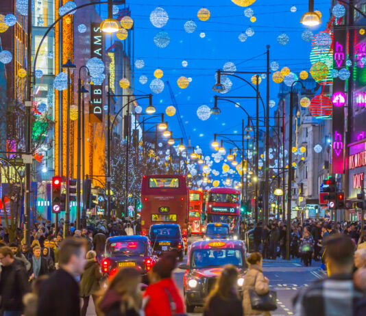 Eine Menschenmenge auf einer Straße in London, die mit Weihnachtsdekoration geschmückt ist.