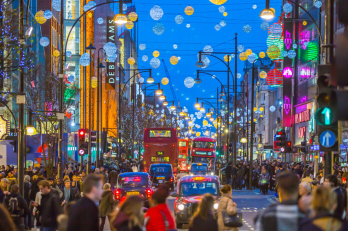 Eine Menschenmenge auf einer Straße in London, die mit Weihnachtsdekoration geschmückt ist.