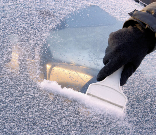 Eine Person befreit die Scheibe eines Autos mit einem Eiskratzer von Eis und Schnee. Das Eiskratzen im Winter ist für viele eine unliebsame Pflicht.