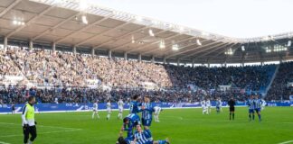 Spieler des Karlsruher SC jubeln mitten im Stadion auf den Ringen sitzen die Fans