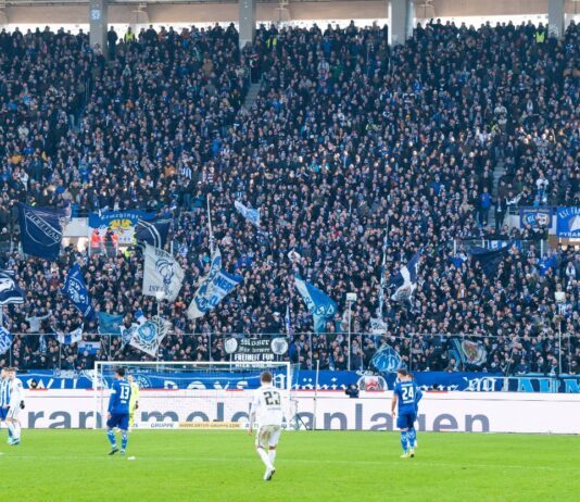 Gleich mehrere Spieler sind auf dem Spielfeld des Karlsruher SC bei einem Fußballspiel angefeuert von den Fans