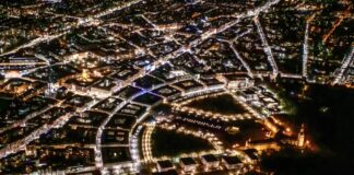 Ein Luftbild von Karlsruhe bei Nacht, die Fächerstadt mit Straßenbeleuchtung. Die Lichter sind angeschaltet in den Wohnungen und Häusern, in denen die Bürger der Fächerstadt leben.