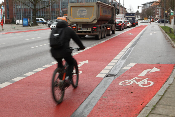 Ein Fahrradfahrer ist auf einem Fahrrad auf einem Radweg durch die Stadt unterwegs