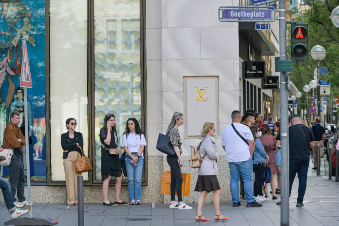 Mehrere Menschen stehen vor einer Filiale von Louis Vuitton.