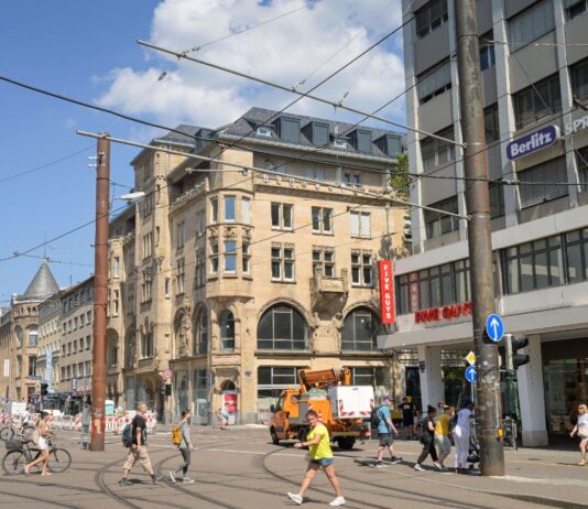Blick auf die Karlsruher Innenstadt mit Passanten und Anwohnern. Die Bürger gehen durch die Straßen, andere Passanten sind beim Einkaufen. Es fahren keine Autos durch das Bild.