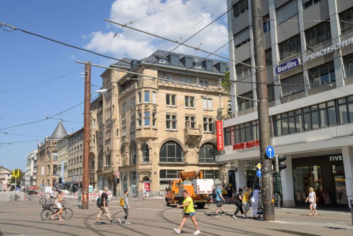 Der Ansicht der Karlsruher Innenstadt mit Passanten und Anwohnern, die über die Straße gehen