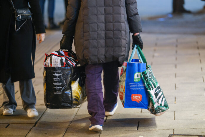 Eine Frau geht mit vielen Einkaufstaschen die Straße entlang.