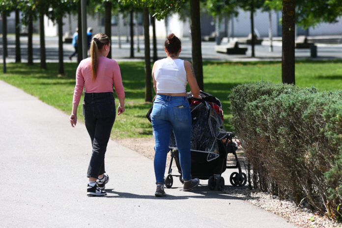 Zwei Frauen gehen mit einem Kinderwagen spazieren.