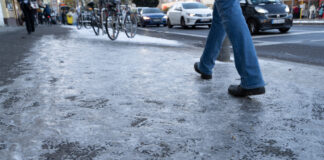 Ein vereister Gehweg in einer Stadt, auf dem ein Mensch läuft. Ein Kälteeinbruch im März droht.