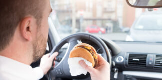 Ein Mann isst einen Burger im Auto.