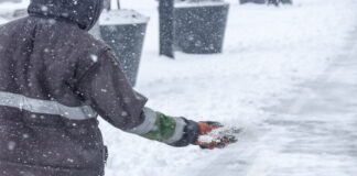 Ein Mann streut Salz, um den Schnee zum Schmelzen zu bringen.